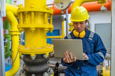 Bir ısıtma tesisinde bakım teknisyeni, Petrokimya işçileri fabrikadaki gaz ve petrol boru hatlarının işleyişini denetliyor, mühendisler işitme koruyucularını birçok boruyla aynı odaya koyuyorlar.