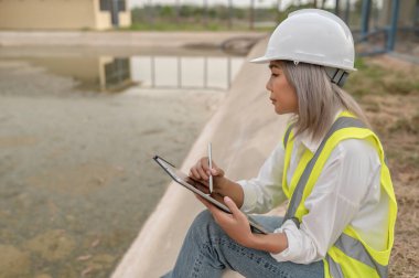 Çevre mühendisleri atık su arıtma tesislerinde, Su geri dönüşüm fabrikasında çalışan su mühendislerinde çalışıyor, teknisyenler ve mühendisler birlikte çalışmayı tartışıyor.