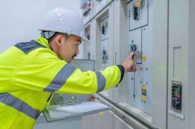 Elektrik mühendisi kontrol odasındaki elektrik dağıtım kabinesinde voltajı kontrol ediyor. Yıllık önleyici bakım, Tayland Elektrikçisi.
