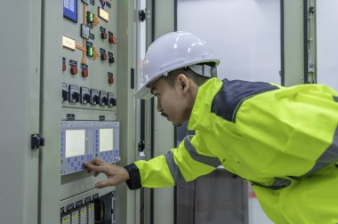 Elektrik mühendisi kontrol odasındaki elektrik dağıtım kabinesinde voltajı kontrol ediyor. Yıllık önleyici bakım, Tayland Elektrikçisi.