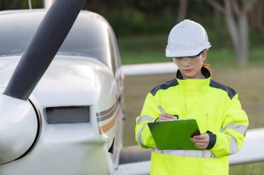 Teknisyen uçağın motorunu tamir ediyor, kadın uzay mühendisliği uçak motorlarını kontrol ediyor, Asyalı tamirci uçak motorlarını kontrol ediyor.