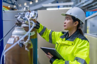 Tayland 'da, ameliyathanede çalışan Asyalı mühendis kask takıyor, özenle ve sabırla çalışıyor, hidrojen tankının valf düzenleyicisini kontrol ediyor..