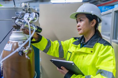 Tayland 'da, ameliyathanede çalışan Asyalı mühendis kask takıyor, özenle ve sabırla çalışıyor, hidrojen tankının valf düzenleyicisini kontrol ediyor..