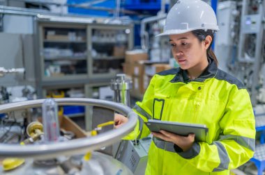 Tayland 'da, ameliyathanede çalışan Asyalı mühendis kask takıyor, özenle ve sabırla çalışıyor, hidrojen tankının valf düzenleyicisini kontrol ediyor..