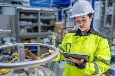 Tayland 'da, ameliyathanede çalışan Asyalı mühendis kask takıyor, özenle ve sabırla çalışıyor, hidrojen tankının valf düzenleyicisini kontrol ediyor..