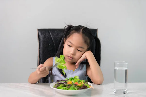 Little asian cute girl refuses to eat healthy vegetables.Nutrition & healthy eating habits for kids concept.Children do not like to eat vegetables.