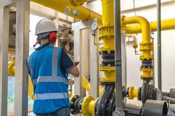 Bir ısıtma tesisinde bakım teknisyeni, Petrokimya işçileri fabrikadaki gaz ve petrol boru hatlarının işleyişini denetliyor, mühendisler işitme koruyucularını birçok boruyla aynı odaya koyuyorlar.