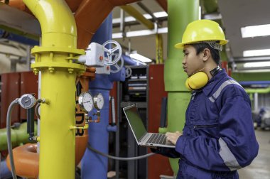 Bir ısıtma tesisinde bakım teknisyeni, Petrokimya işçileri fabrikadaki gaz ve petrol boru hatlarının işleyişini denetliyor, mühendisler işitme koruyucularını birçok boruyla aynı odaya koyuyorlar.