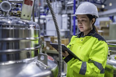 Tayland 'da, ameliyathanede çalışan Asyalı mühendis kask takıyor, özenle ve sabırla çalışıyor, hidrojen tankının valf düzenleyicisini kontrol ediyor..