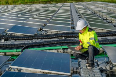 Yüzen güneş enerjisi santralinde çalışan Asyalı mühendis, yenilenebilir enerji, teknisyen ve yatırımcı güneş panelleri güneş enerjisi kurulumundaki panelleri kontrol ediyor