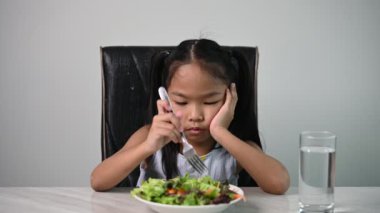Sağlıklı sebze yemesi için Asyalı tatlı bir kız. Çocuk konsepti için beslenme ve sağlıklı yeme alışkanlıkları. Çocuklar mutlu ve sebze yemekten hoşlanırlar..