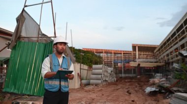 Büyük bir inşaat projesinin şantiyesinde çalışan Asyalı mühendis. Taylandlılar. İnşaat alanında fazla mesai