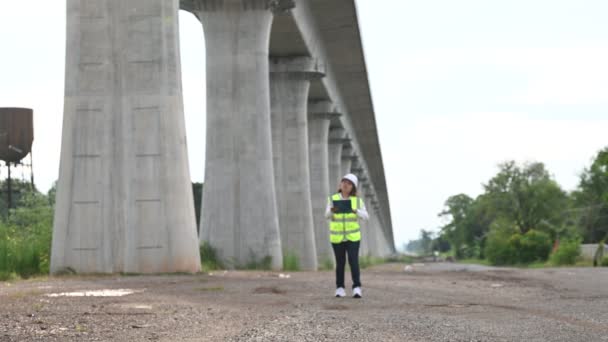 Asiatisk Kvinnlig Ingenjör Arbetar Byggarbetsplats För Motorvägsbro Arbetstagare Som Inspekterar — Stockvideo