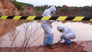 Su analizi üzerinde çalışan koruyucu üniforma giyen bilim adamları ya da biyologlar. Çevre mühendisleri tehlikeli alanlarda su kalitesini kontrol ederler.