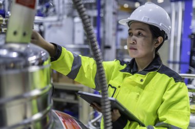 Ameliyathanede çalışan Asyalı mühendis. Taylandlılar kask takar. Adam özenle ve sabırla çalışmış, kadın hidrojen tankındaki valf düzenleyicisini kontrol etmiş..