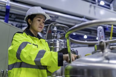 Ameliyathanede çalışan Asyalı mühendis. Taylandlılar kask takar. Adam özenle ve sabırla çalışmış, kadın hidrojen tankındaki valf düzenleyicisini kontrol etmiş..