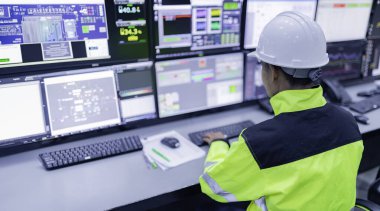 Kontrol odasında çalışan bir mühendis. Yönetici kontrol sistemi. Birçok monitörden teknisyen izleme programı