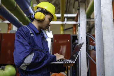 Isıtma tesisinde bakım teknisyeni. Petrokimya işçisi fabrikadaki gaz ve petrol boru hatlarının işletilmesini denetliyor. Mühendis işitme koruyucuyu birçok boruyla aynı odaya koydu.