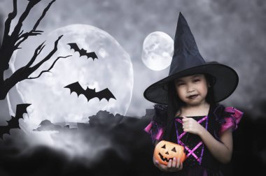 Asyalı sevimli bayan çocuk balkabağıyla cadı kostümü giyiyor. Cadılar Bayramı festivali