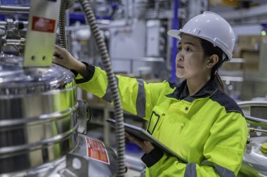 Ameliyathanede çalışan Asyalı mühendis. Taylandlılar kask takar. Adam özenle ve sabırla çalışmış, kadın hidrojen tankındaki valf düzenleyicisini kontrol etmiş..