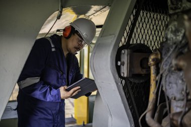 Makine mühendisi fabrikadaki büyük makineleri inceliyor. Demiryolu motor bakım teknisyeni, motor tamircisi.