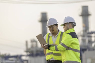 Petrol ve gaz rafinerisi fabrikasında çalışan Asyalı grup petrokimya mühendisleri. İşçi erkek mühendisler elektrik santrali enerji üretiminde kontrolde çalışıyorlar.