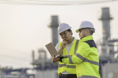 Petrol ve gaz rafinerisi fabrikasında çalışan Asyalı grup petrokimya mühendisleri. İşçi erkek mühendisler elektrik santrali enerji üretiminde kontrolde çalışıyorlar.