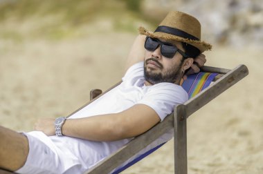 Deniz sahilinde oturan Asyalı adam. Yazın dinlenme zamanı.