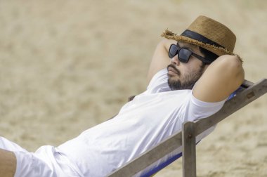 Deniz sahilinde oturan Asyalı adam. Yazın dinlenme zamanı.