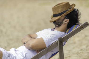 Deniz sahilinde oturan Asyalı adam. Yazın dinlenme zamanı.