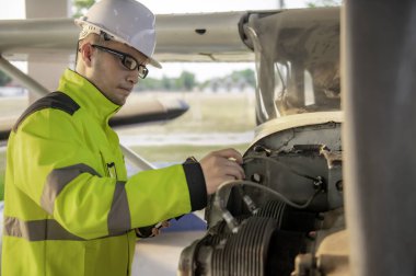 Teknisyen uçağın motorunu tamir ediyor. Erkek havacılık mühendisliği uçak motorlarını kontrol ediyor. Asyalı tamirci uçak motorunu inceliyor