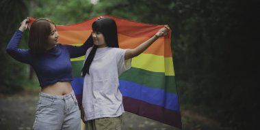 Kızla birlikte iki kız. LGBT Gurur Ayı konsepti. Asyalı güzel kadınlar bez giyer. Gay Özgürlük Günü. Beyaz arkaplanda ikili olmayan portre