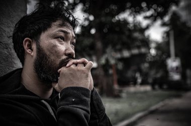 Asyalı adam yan yolda evsiz. Bir yabancı, ailesi olmadığı için yolda tek başına yaşamak zorundadır..