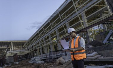 Büyük bir inşaat projesinin şantiyesinde çalışan Asyalı mühendis. Taylandlılar. İnşaat alanında fazla mesai