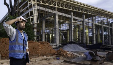 Büyük bir inşaat projesinin şantiyesinde çalışan Asyalı mühendis. Taylandlılar. İnşaat alanında fazla mesai