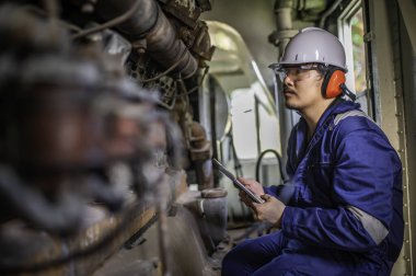 Makine mühendisi fabrikadaki büyük makineleri inceliyor. Demiryolu motor bakım teknisyeni, motor tamircisi.