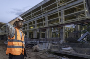 Büyük bir inşaat projesinin şantiyesinde çalışan Asyalı mühendis. Taylandlılar. İnşaat alanında fazla mesai