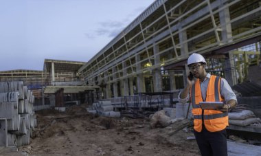 Büyük bir inşaat projesinin şantiyesinde çalışan Asyalı mühendis. Taylandlılar. İnşaat alanında fazla mesai