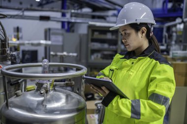 Ameliyathanede çalışan Asyalı mühendis. Taylandlılar kask takar. Adam özenle ve sabırla çalışmış, kadın hidrojen tankındaki valf düzenleyicisini kontrol etmiş..