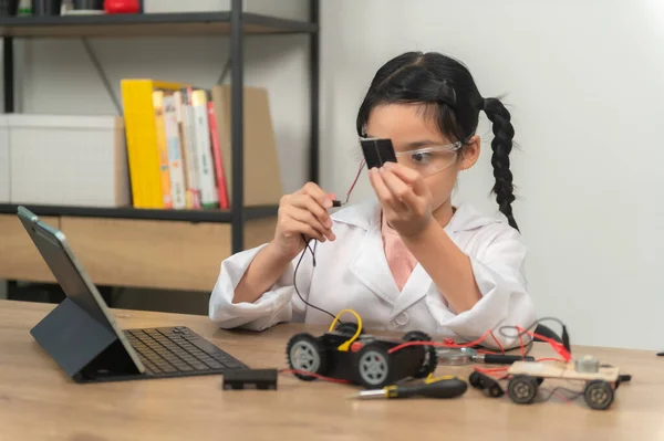 Asian littlle girl constructing and coding robot at STEM class. Fixing and repair mechanic toy car