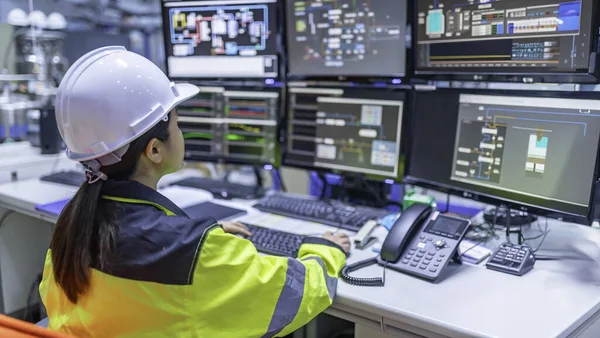 Büyük Endüstri Fabrikası Kadın Bilgisayar Mühendisi Kişisel Bilgisayar 'da çalışıyor. Kontrol makinesi için program kodluyor. Taylandlılar dört monitörle çalışıyorlar. Ciddi ile çalışan programcı