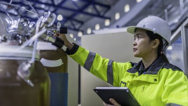 Ameliyathanede çalışan Asyalı mühendis. Taylandlılar kask takar. Adam özenle ve sabırla çalışmış, kadın hidrojen tankındaki valf düzenleyicisini kontrol etmiş..