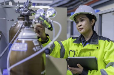 Ameliyathanede çalışan Asyalı mühendis. Taylandlılar kask takar. Adam özenle ve sabırla çalışmış, kadın hidrojen tankındaki valf düzenleyicisini kontrol etmiş..