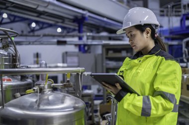 Ameliyathanede çalışan Asyalı mühendis. Taylandlılar kask takar. Adam özenle ve sabırla çalışmış, kadın hidrojen tankındaki valf düzenleyicisini kontrol etmiş..