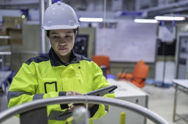 Ameliyathanede çalışan Asyalı mühendis. Taylandlılar kask takar. Adam özenle ve sabırla çalışmış, kadın hidrojen tankındaki valf düzenleyicisini kontrol etmiş..