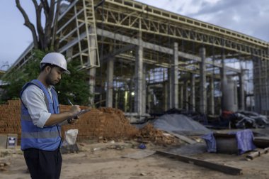 Büyük bir inşaat projesinin şantiyesinde çalışan Asyalı mühendis. Taylandlılar. İnşaat alanında fazla mesai