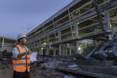Büyük bir inşaat projesinin şantiyesinde çalışan Asyalı mühendis. Taylandlılar. İnşaat alanında fazla mesai