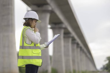 Otoyol köprüsü inşaatında çalışan Asyalı bir kadın mühendis. Sınır ötesi inşaatı denetleyen memur.