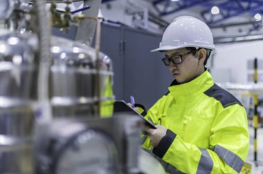 Ameliyathanede çalışan Asyalı mühendis. Taylandlılar kask takar. Çalışkanlık ve sabırla çalıştı, hidrojen tankındaki kapakçık düzenleyicisini kontrol etti..