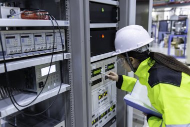 Elektrik mühendisi kadın kontrol odasındaki elektrik dağıtım kabinesindeki voltajı kontrol ediyor. Yıllık önleyici bakım. Tayland Elektrikçisi şirkette çalışıyor.